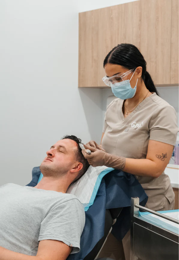 Person receiving a hair treatment from a professional in a clinical setting